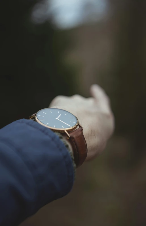 a hand with a gold wrist watch is in the dark