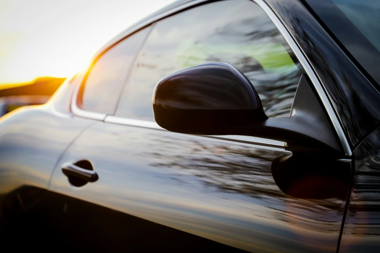 car with side mirror and door mirror reflecting the setting sun