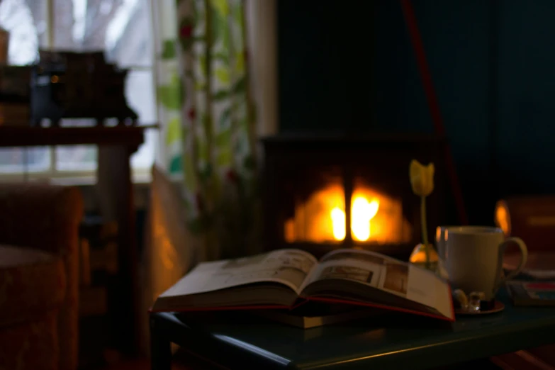 a book sitting on a table with a cup and candle