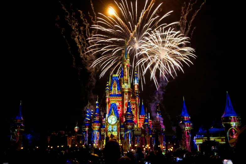 a colorful castle lit up at night with bright lights and fireworks