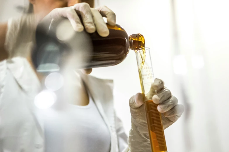 a woman wearing a glove pouring out honey from a bottle