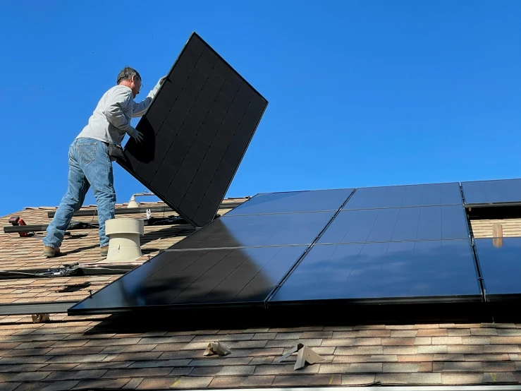 a man that is standing on a roof with a solar panel on