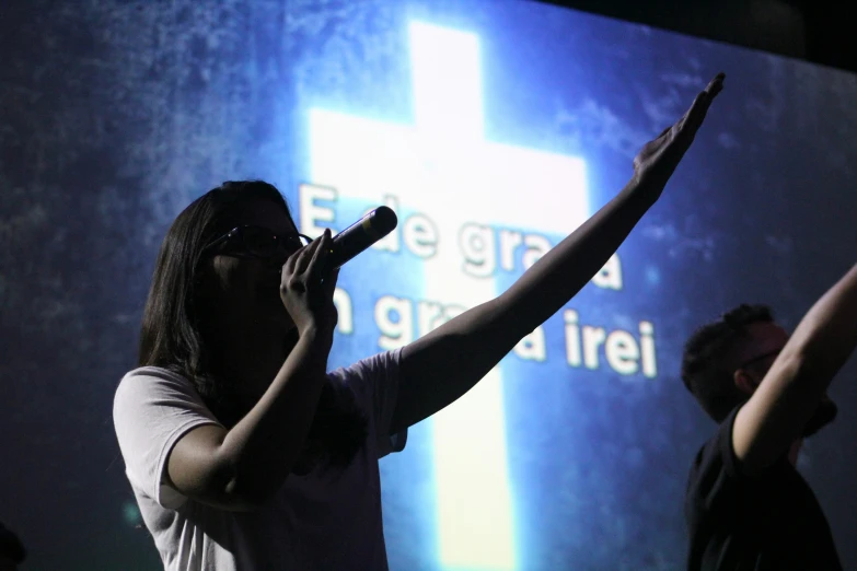 two people in front of a light and a cross on a screen