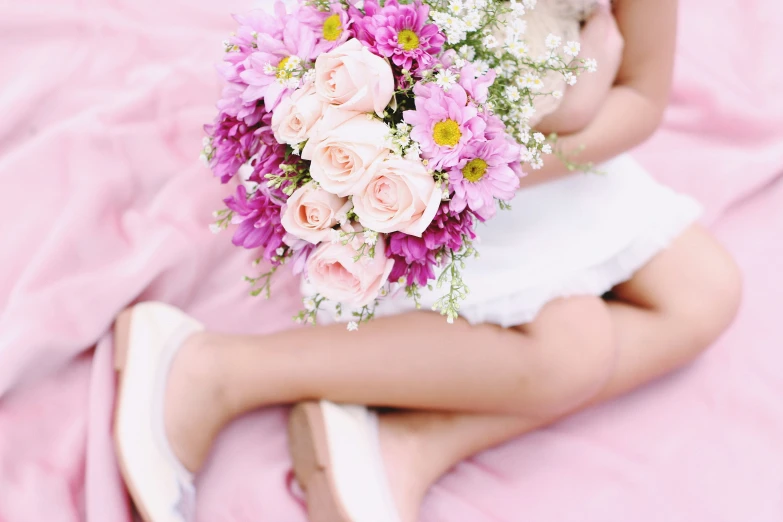 a person laying down on a pink bed next to flowers