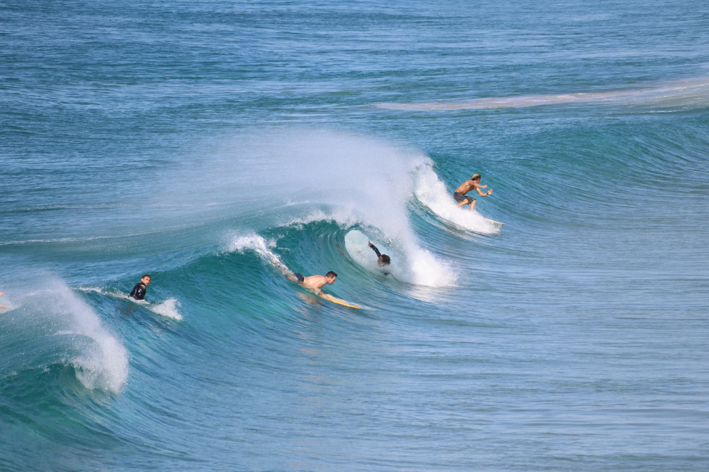 surfers in the middle of a wave with the sky and water blue