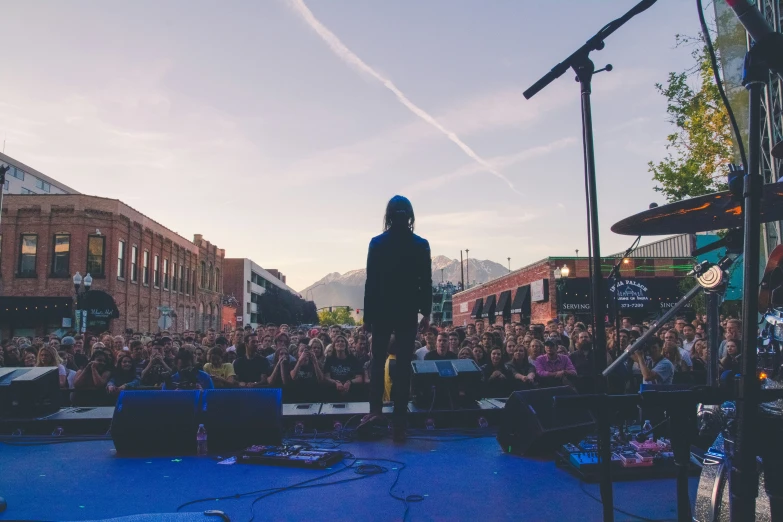 a guy standing on a stage with a microphone at sunset