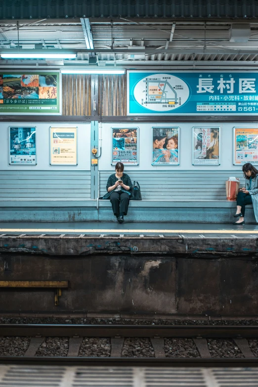 two people sitting on a bench in front of a train