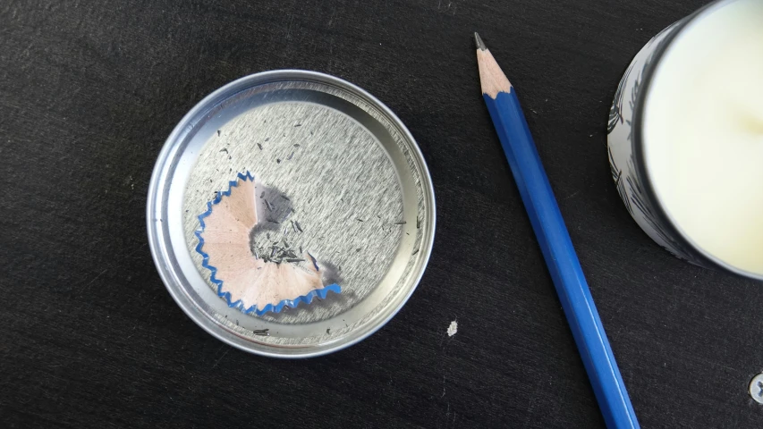 a pencil on top of a can and a cup of milk