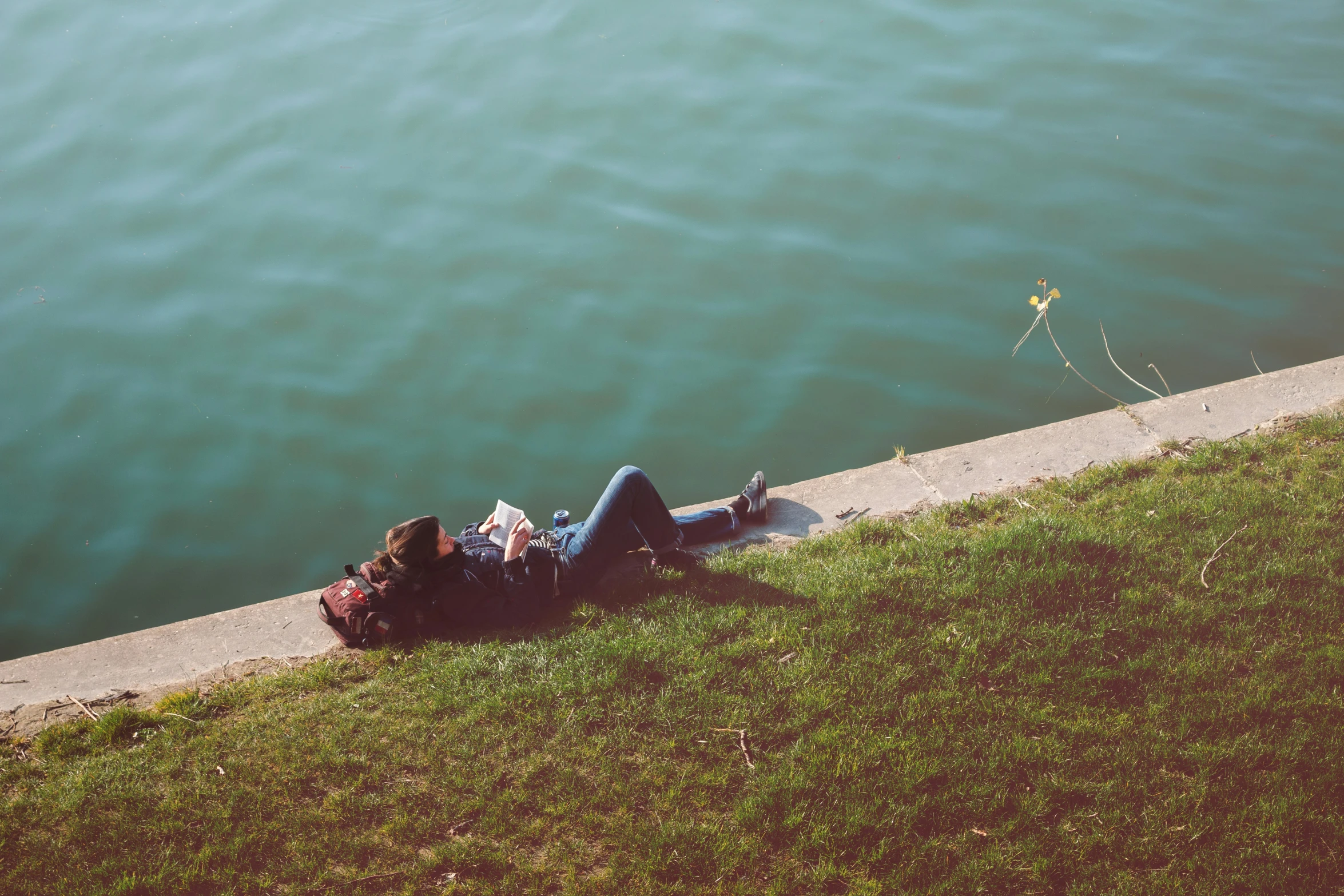 a woman that is laying on the ground near water