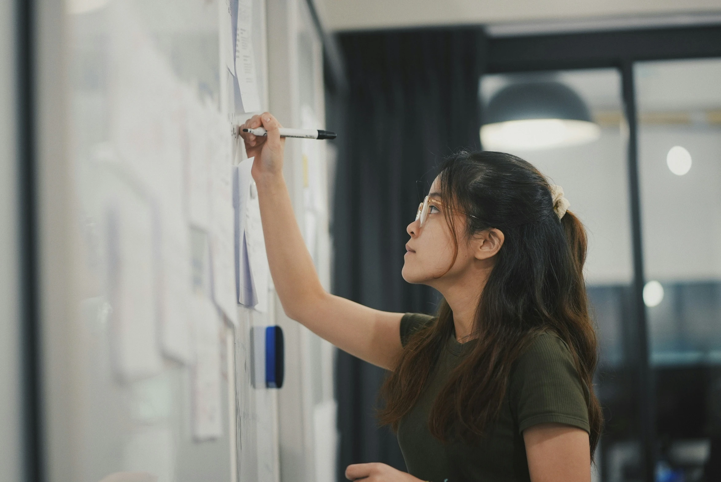 a woman is working with some markers on a wall