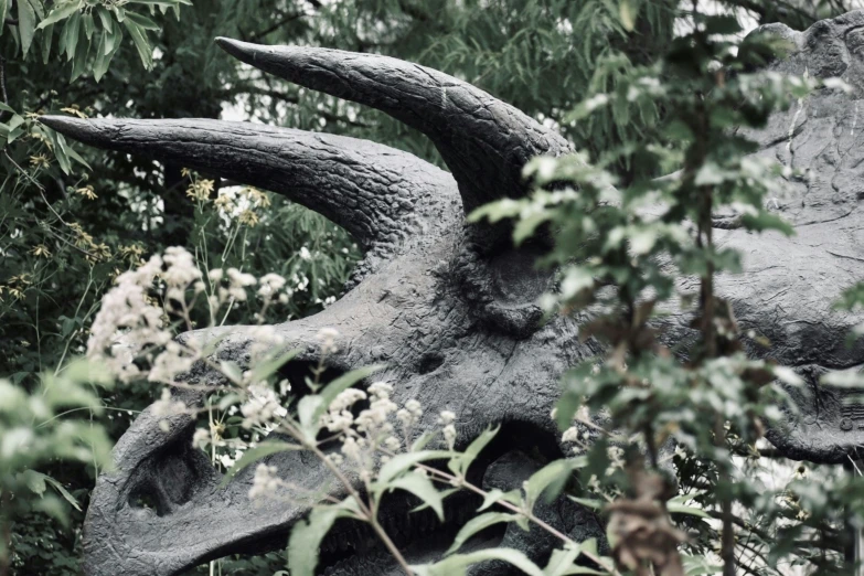 two fake horned sheep in a field covered in trees and flowers