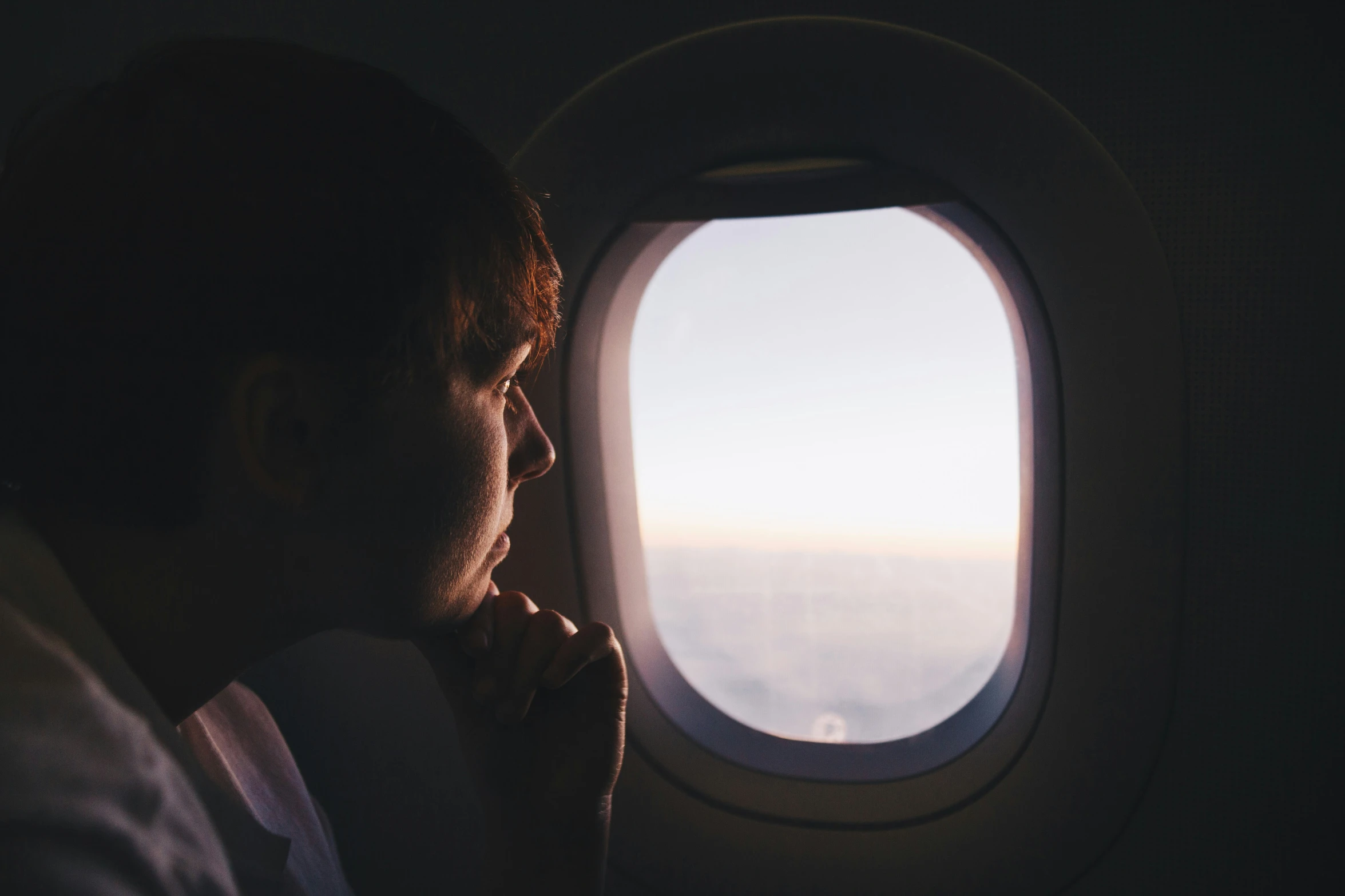 man looking out of airplane window at the view outside