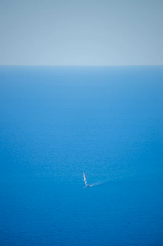 the sailboat is riding in the middle of a large ocean