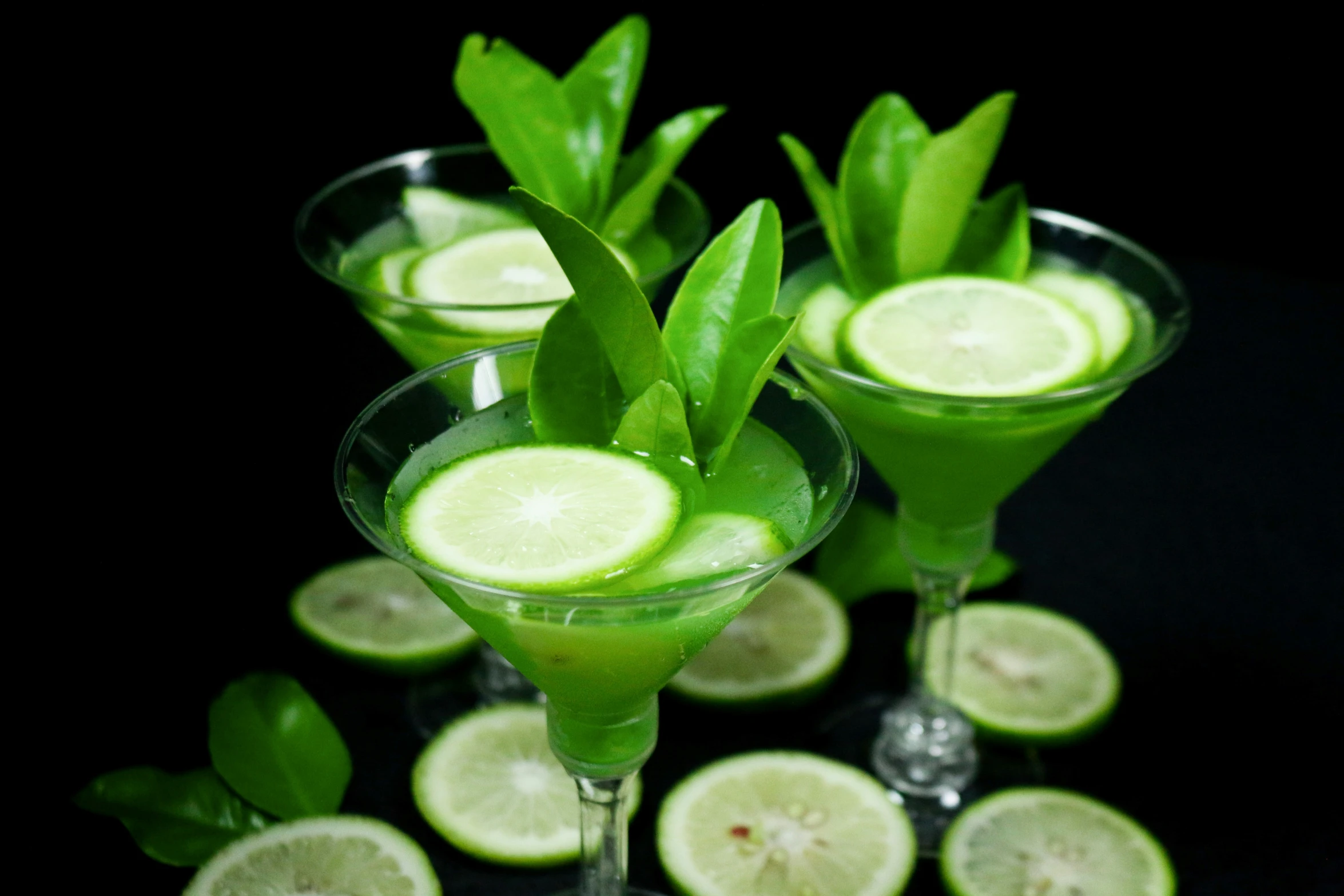 three glasses filled with fruit and green drinks