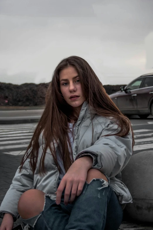 a girl with long hair is sitting on a curb