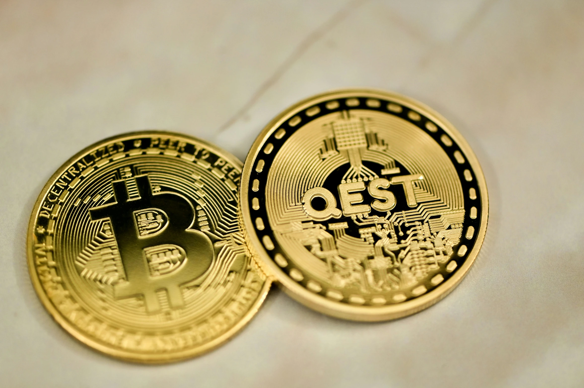 two golden bitcoins placed side by side on a white surface