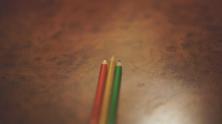 three colored pencils sitting next to each other