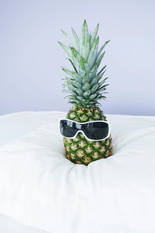 a pineapple wearing sunglasses sitting on top of a pillow