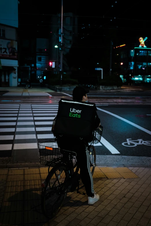 man sitting on bike with back pack in middle of city at night