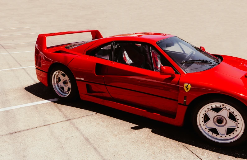 a red ferrari is parked in an empty lot