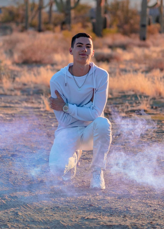 a man kneeling in the dirt in front of a cactus