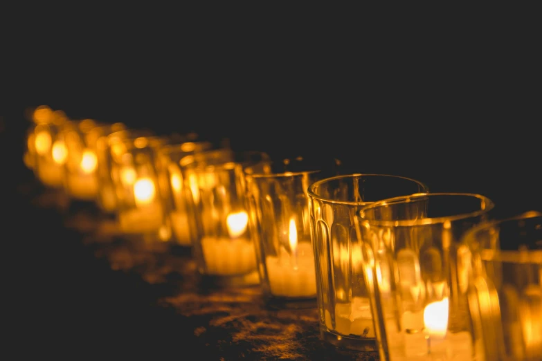 rows of candles in glass cases with only one candle lit up