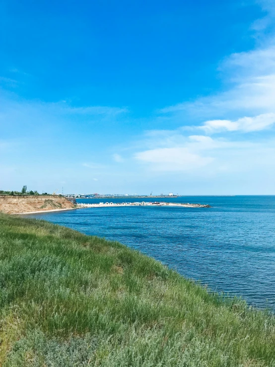 a grassy hill with a long body of water