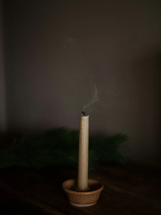 a candle burning on a small dish on a wooden table