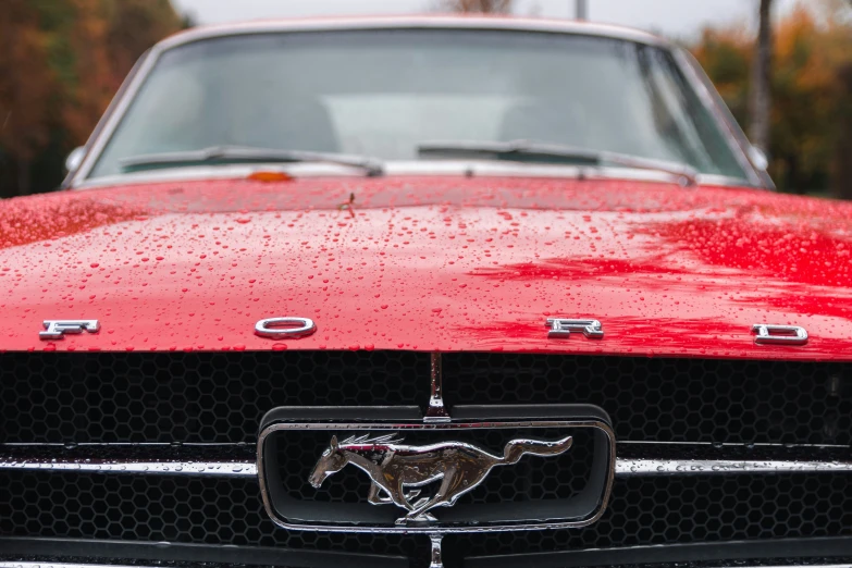 a red mustang hood ornament in the shape of a mustang emblem