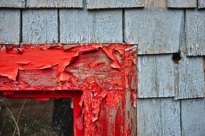 red paint on the side of a grey wooden building