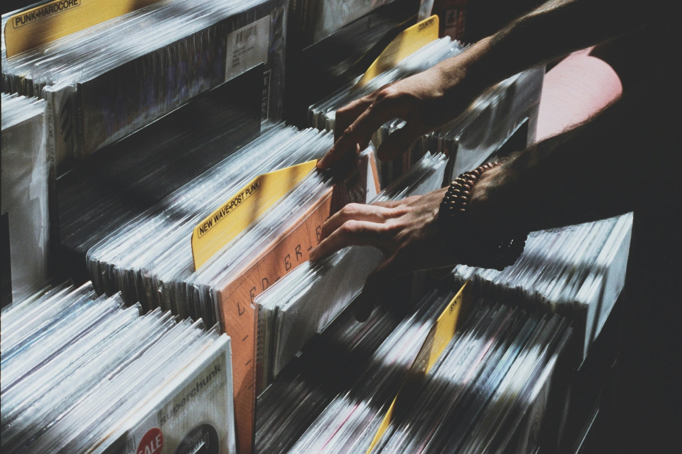 a person's hand moving a stack of records from boxes to a record player