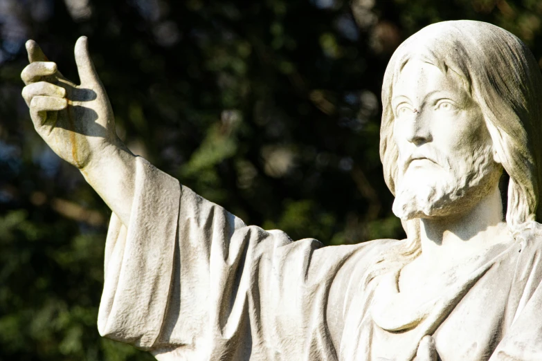 a statue of jesus with a hand up and peace fingers in the air