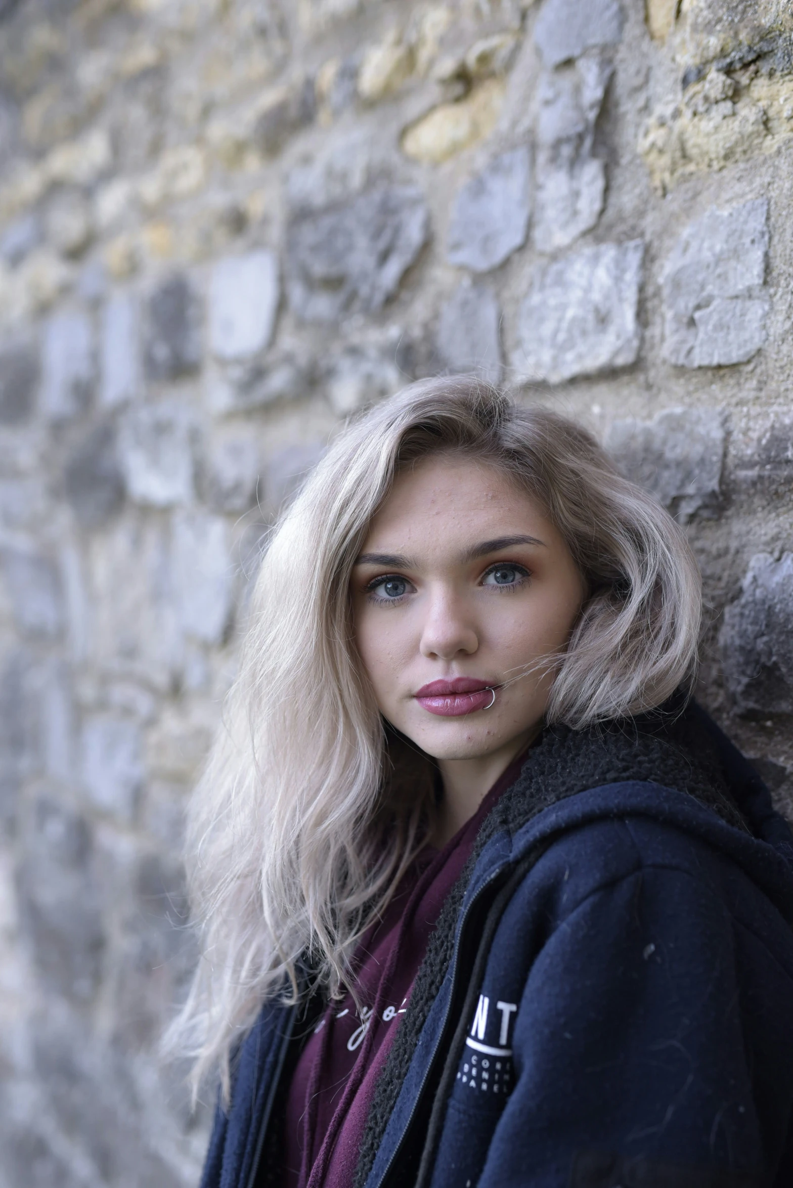 a woman in black jacket next to a brick wall