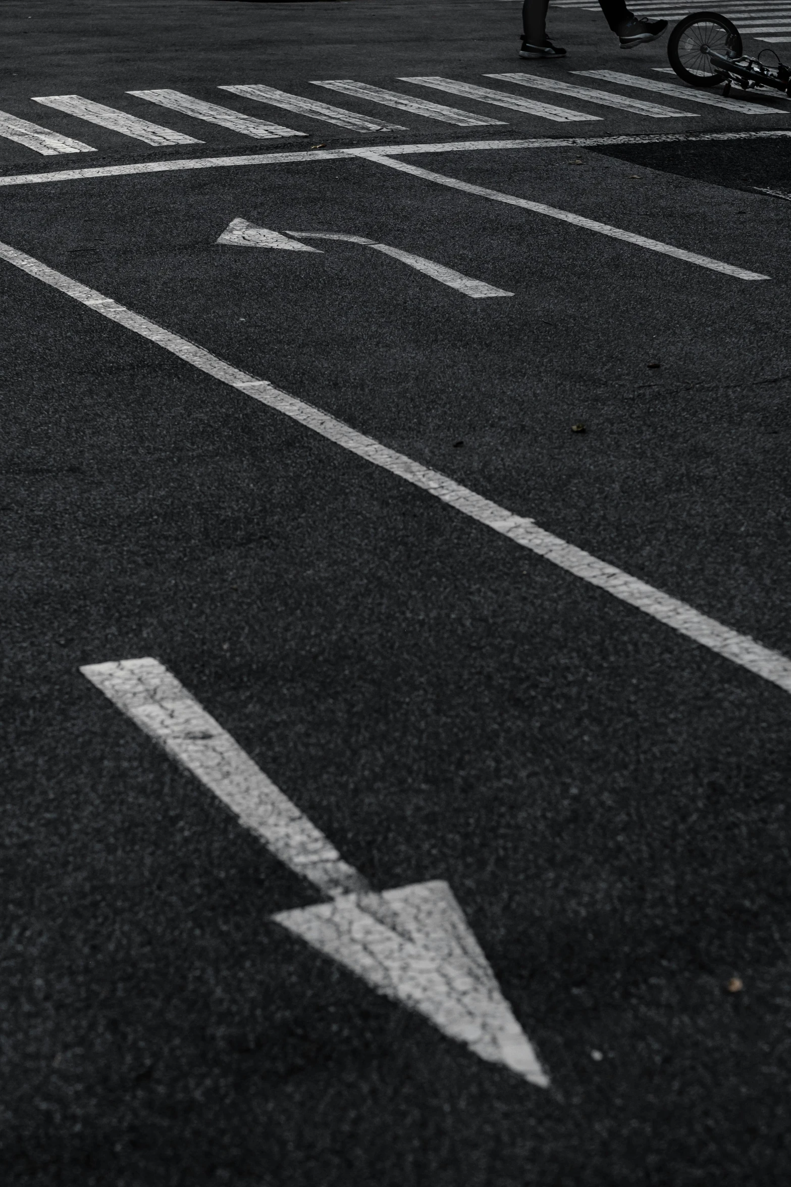 a person walking down an asphalt road next to an arrow sign