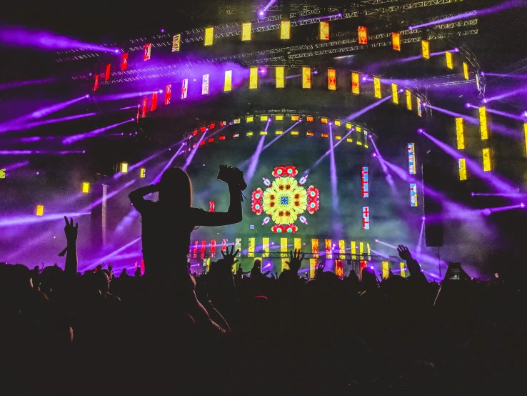 people standing in front of an illuminated stage during a concert