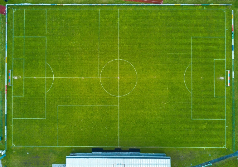 a large soccer field with grass and buildings