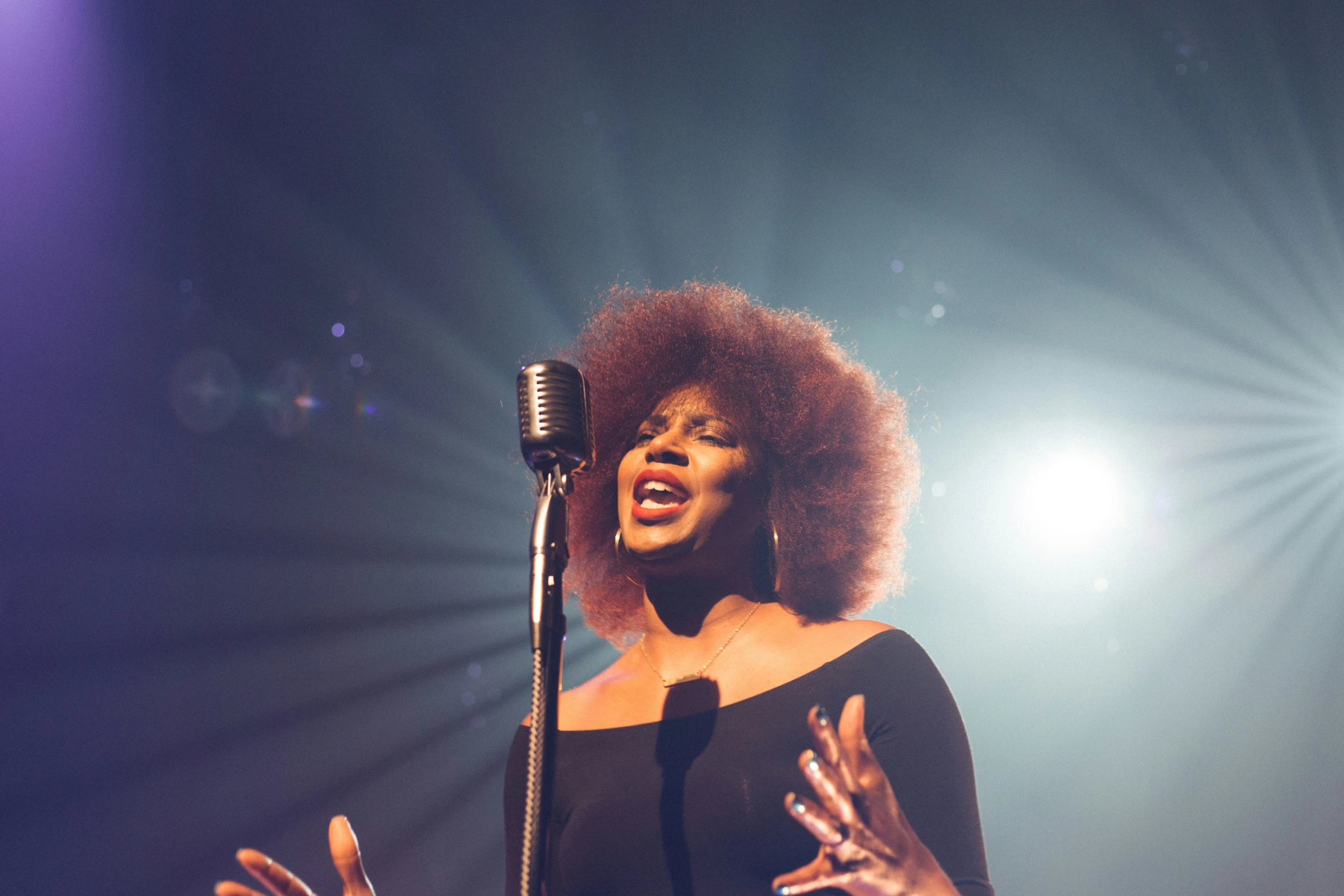 woman singing into a microphone in front of the crowd