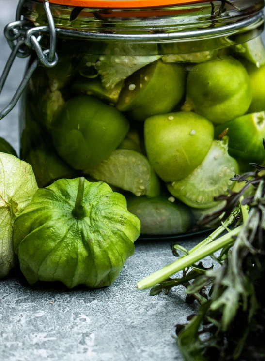 green vegetables sitting on a table, in a glass jar