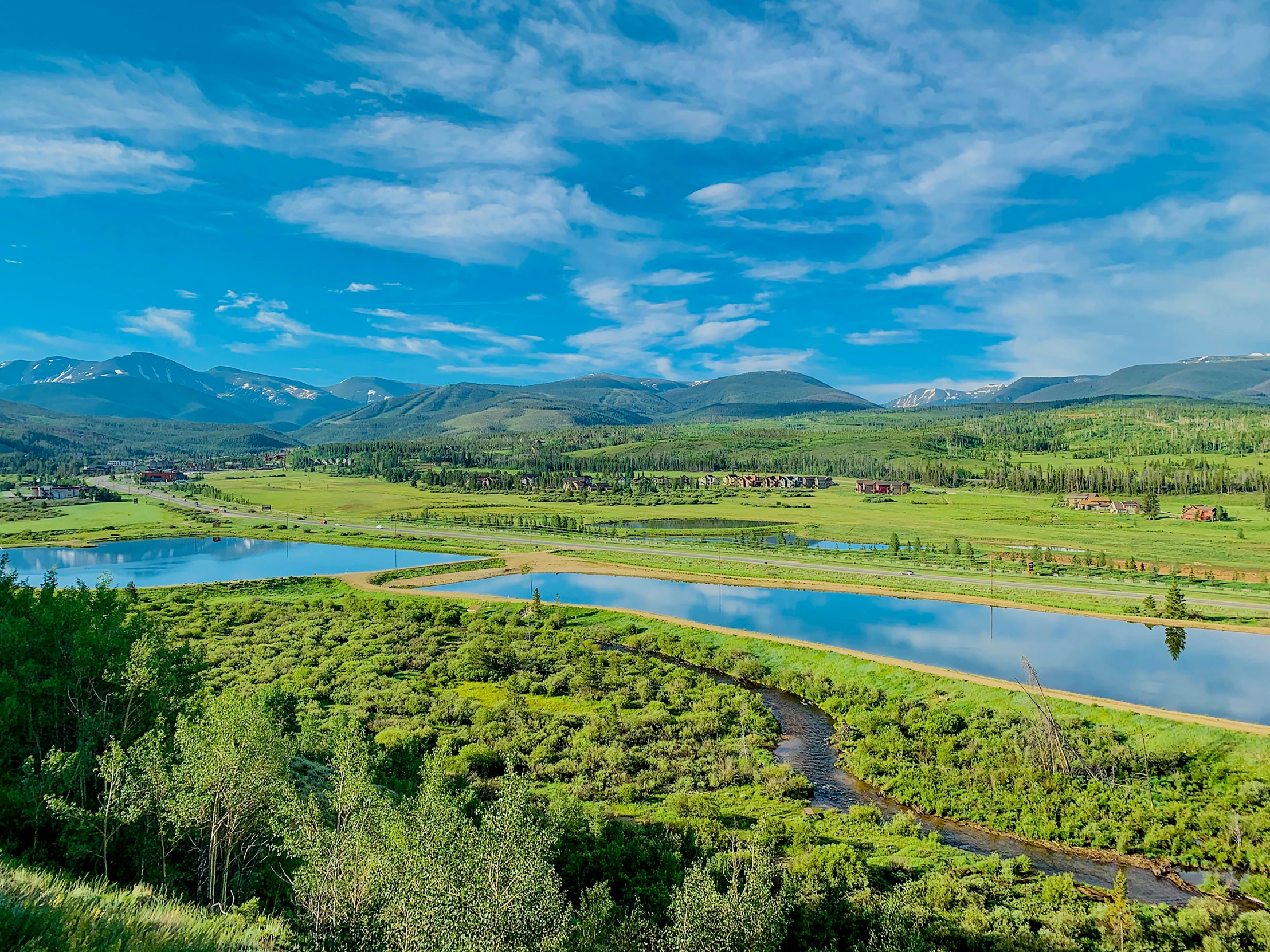 the view from a hill of a pond with hills in the distance