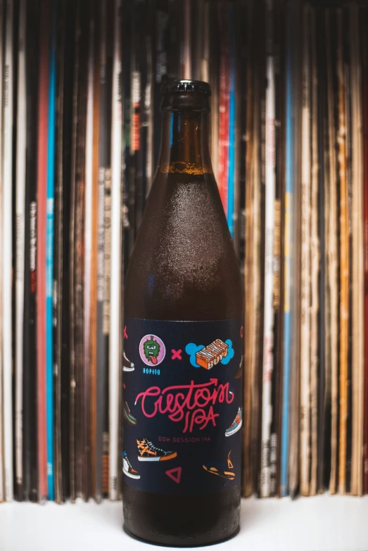 a close up of a bottle of beer in front of some records