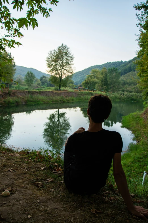 a man is sitting on the ground near the water