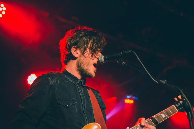 man with a guitar in his hand and microphone near him