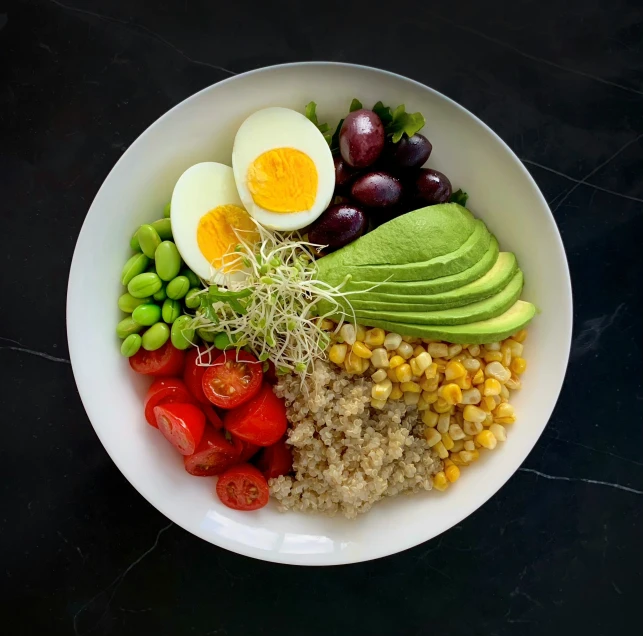 a white bowl containing some vegetables and eggs on a table