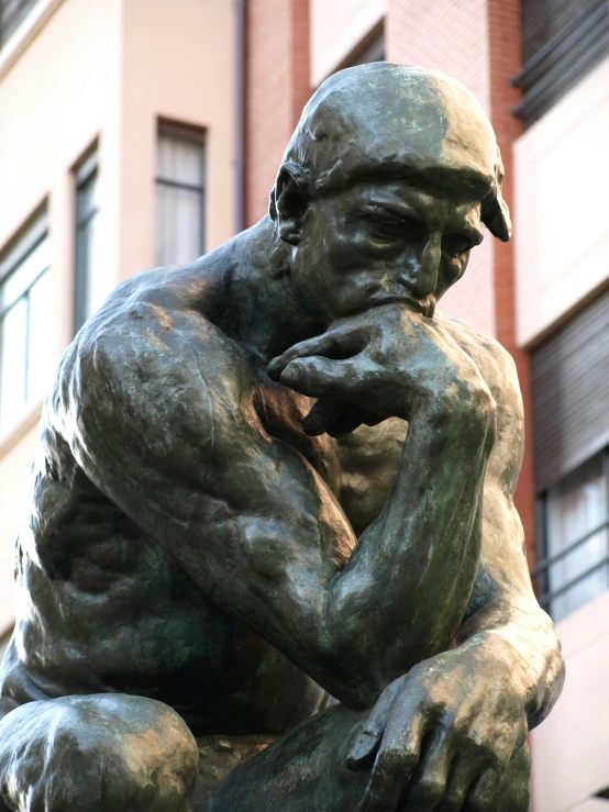 a bronze statue of a man has his hands on his chin