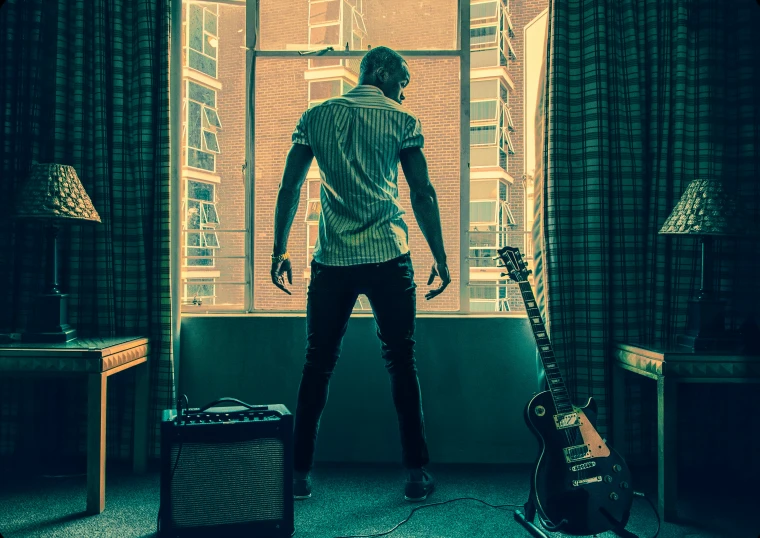 a man looking at an acoustic guitar, with the sunlight coming through a window