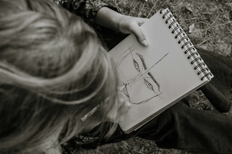 child holding note book while drawing in field