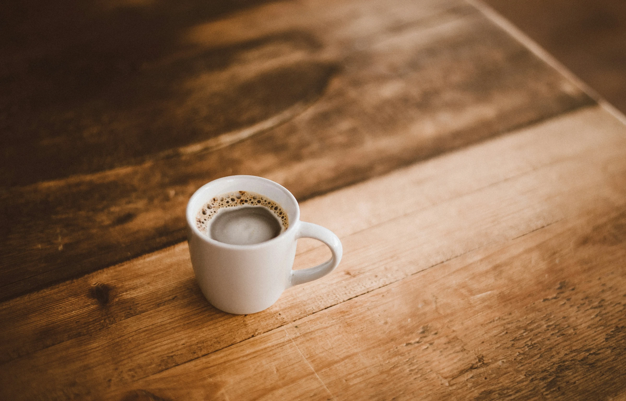 coffee is being put into a cup on a wooden table