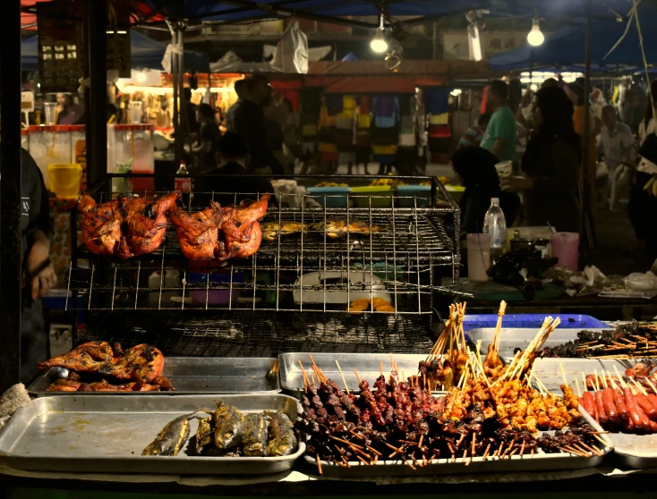 various meats are being cooked in bins at an open air market