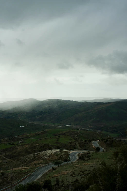 a hilly landscape with many small roads under a stormy sky