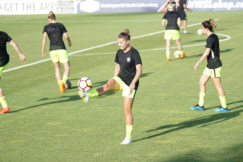 female soccer players are practicing kicking the ball
